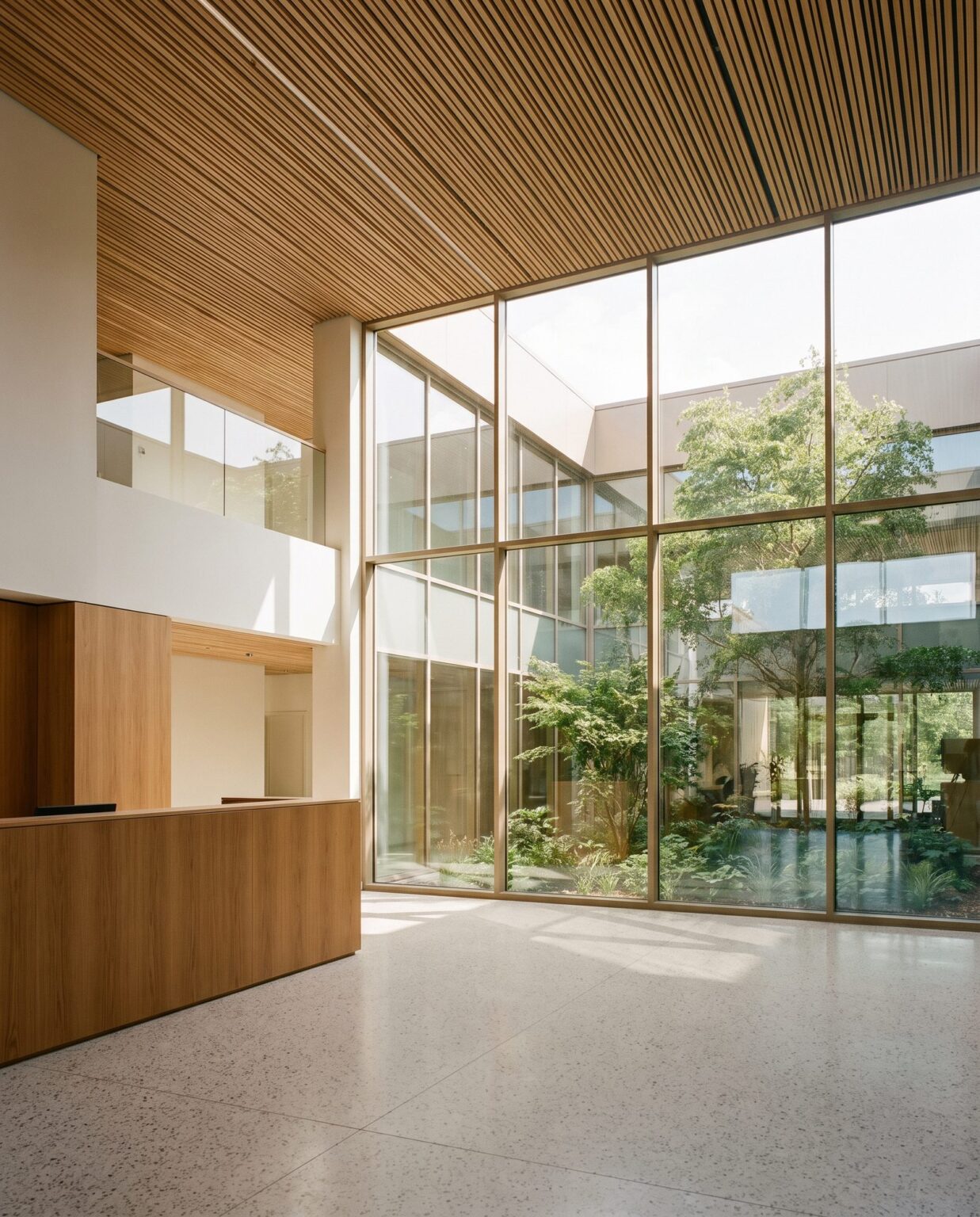 Double-height hospital lobby in light oak and glass